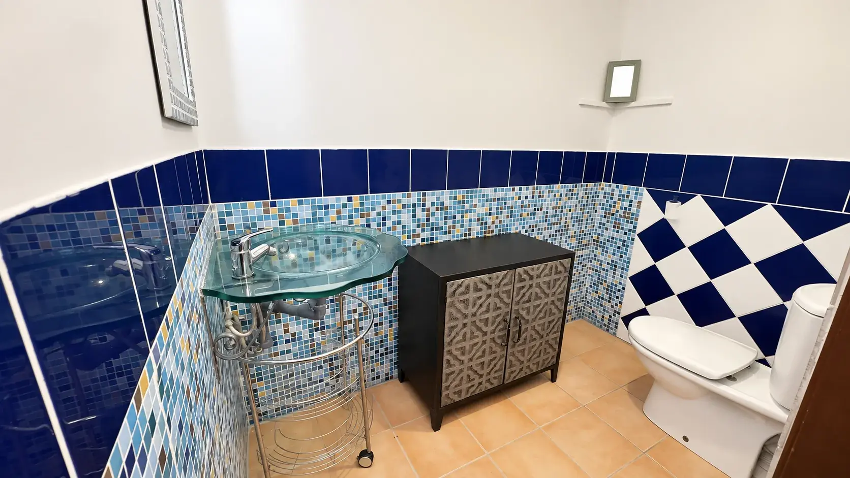 Baño con azulejos azules y lavabo de cristal