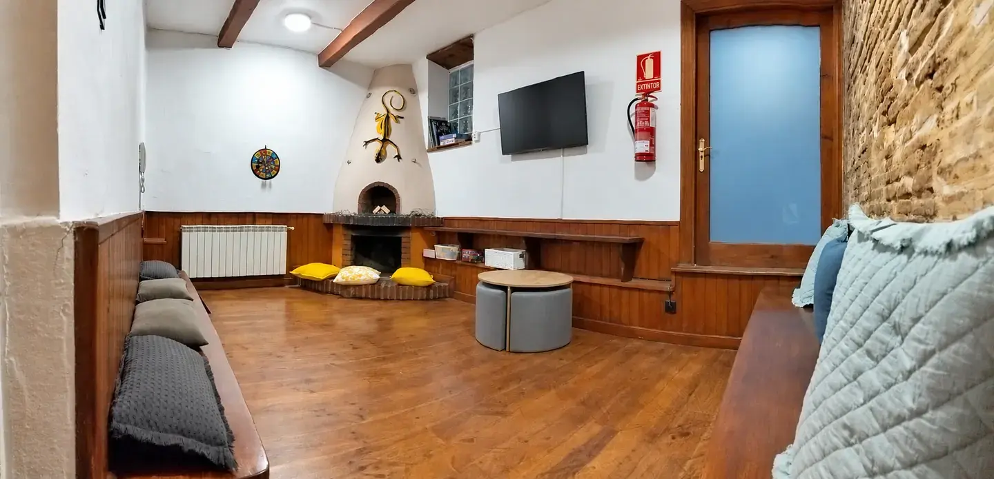 Sala infantil con bancos de madera y cojines junto a la chimenea